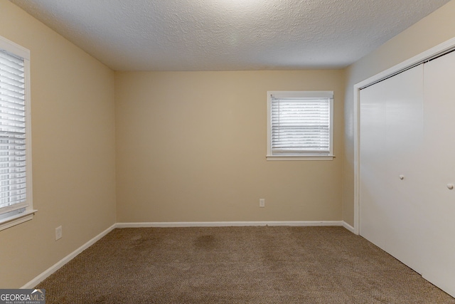 unfurnished bedroom with a textured ceiling, a closet, and carpet floors