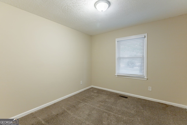 empty room with a textured ceiling and carpet floors