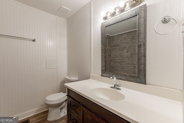 bathroom featuring vanity, a textured ceiling, wood walls, hardwood / wood-style flooring, and toilet