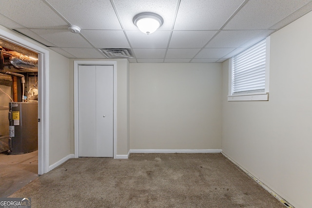 unfurnished bedroom featuring a drop ceiling, carpet, water heater, and a closet