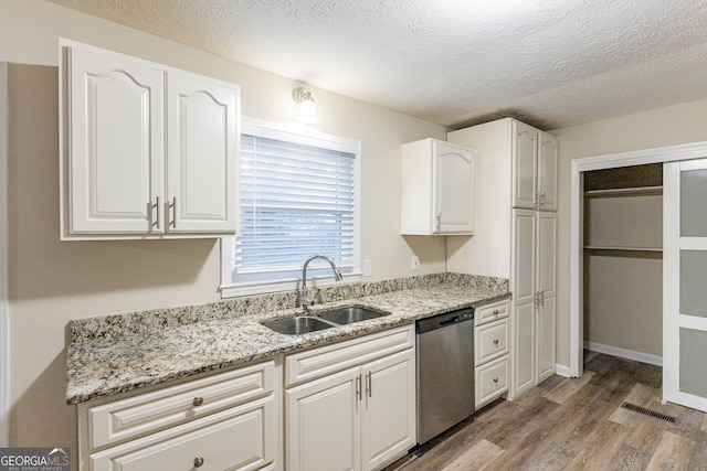 kitchen featuring dishwasher, white cabinets, a textured ceiling, sink, and light hardwood / wood-style flooring