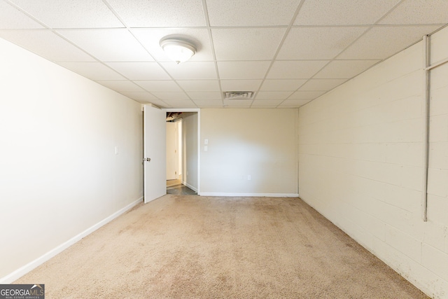 carpeted empty room featuring a drop ceiling