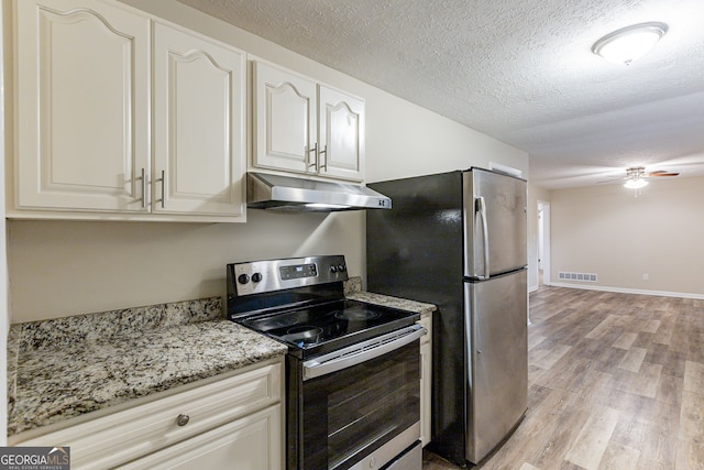 kitchen featuring light stone counters, a textured ceiling, ceiling fan, light wood-type flooring, and appliances with stainless steel finishes