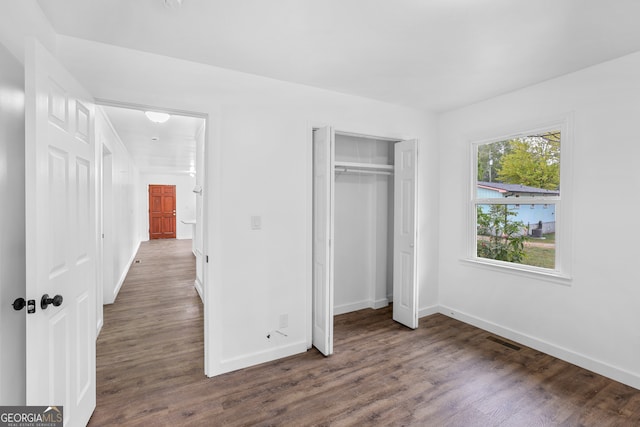 unfurnished bedroom with dark hardwood / wood-style flooring and a closet