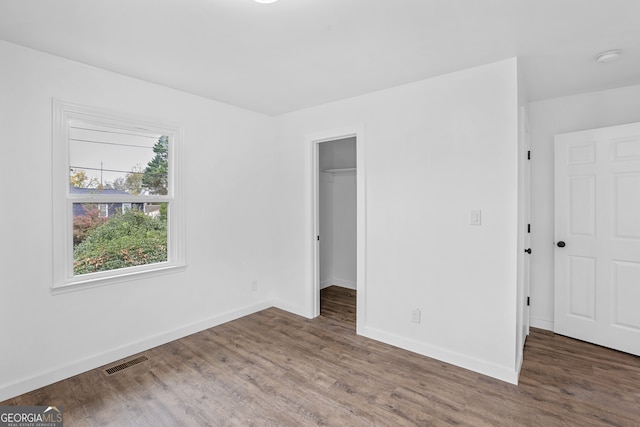 unfurnished bedroom featuring a closet, a spacious closet, and dark hardwood / wood-style floors