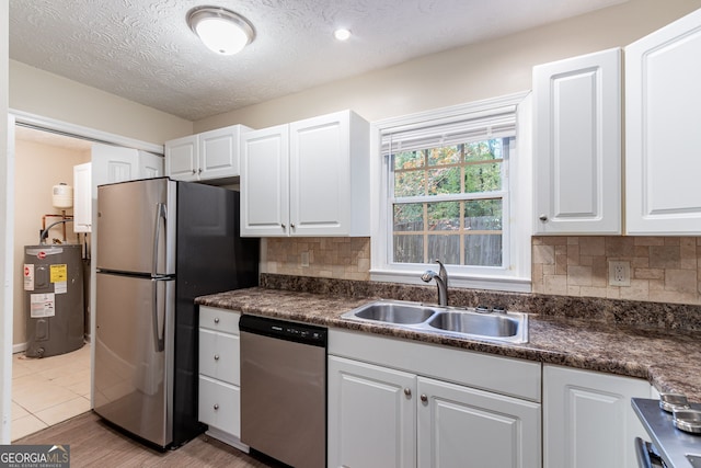 kitchen with white cabinets, appliances with stainless steel finishes, sink, and electric water heater