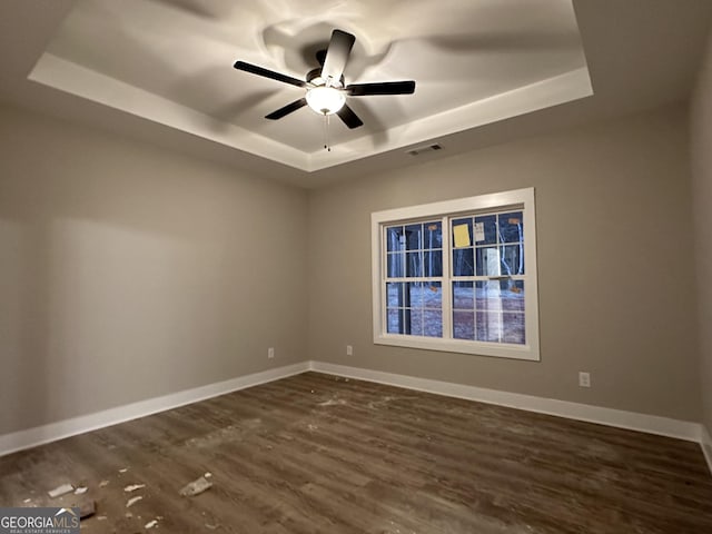 spare room with ceiling fan, a raised ceiling, and dark hardwood / wood-style floors