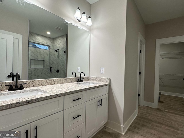 bathroom with walk in shower, vanity, and hardwood / wood-style flooring