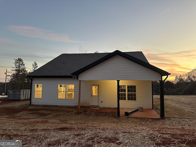 back house at dusk featuring a patio area