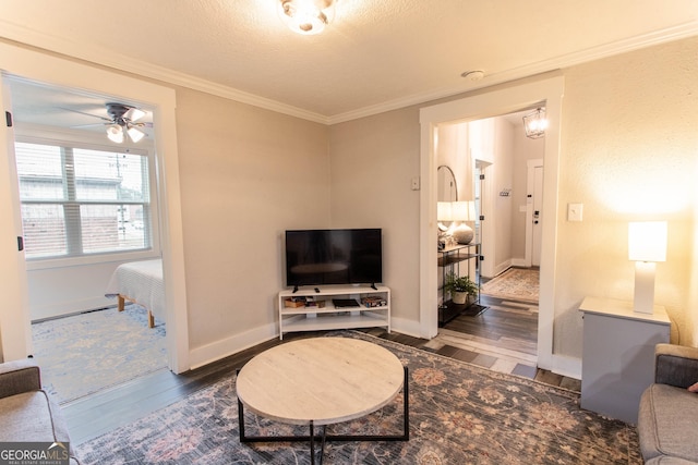 living room with ceiling fan, baseboards, crown molding, and wood finished floors