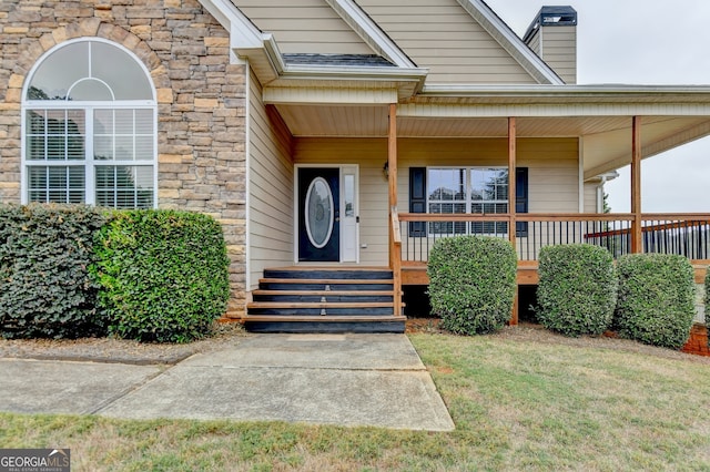 view of exterior entry with a yard and covered porch