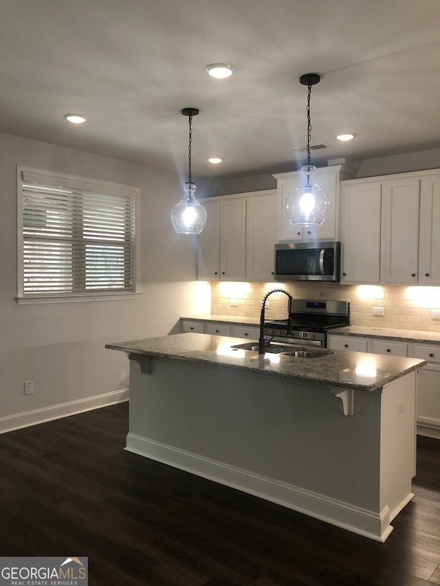 kitchen featuring a kitchen island with sink, stainless steel appliances, dark wood-type flooring, and sink