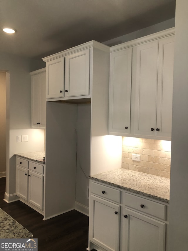 kitchen with dark wood-type flooring, white cabinetry, backsplash, and light stone counters