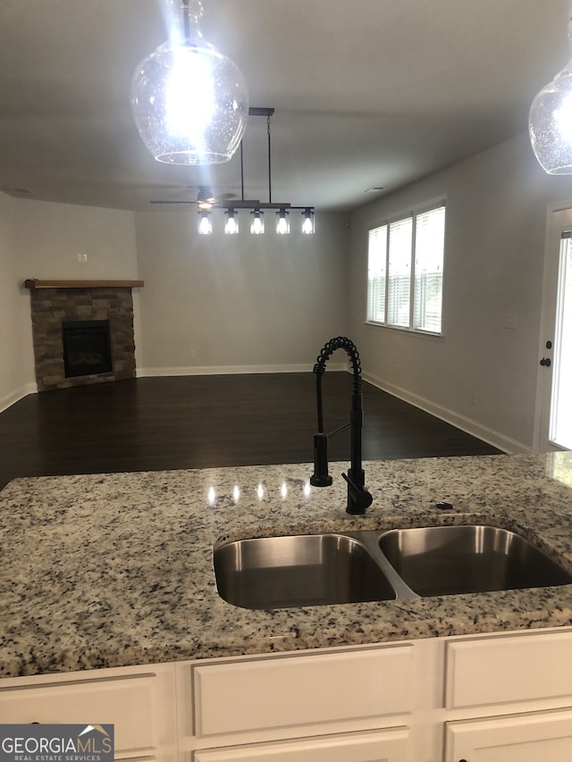 kitchen featuring hanging light fixtures, light stone countertops, sink, and dark hardwood / wood-style flooring