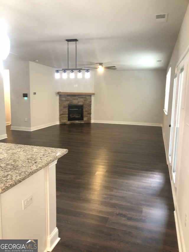 unfurnished living room featuring dark hardwood / wood-style floors and a stone fireplace