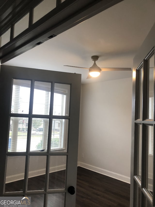 spare room with dark wood-type flooring, a wealth of natural light, and ceiling fan