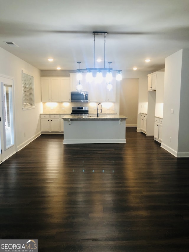 kitchen with a kitchen island with sink, appliances with stainless steel finishes, dark hardwood / wood-style floors, and decorative light fixtures