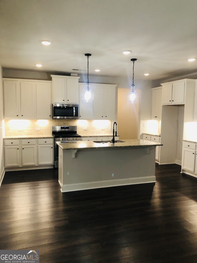 kitchen with stainless steel appliances, sink, dark wood-type flooring, and decorative light fixtures