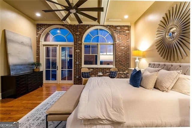 bedroom with french doors, brick wall, and hardwood / wood-style flooring