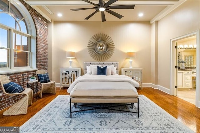 bedroom featuring ensuite bathroom, brick wall, ceiling fan, and dark hardwood / wood-style floors