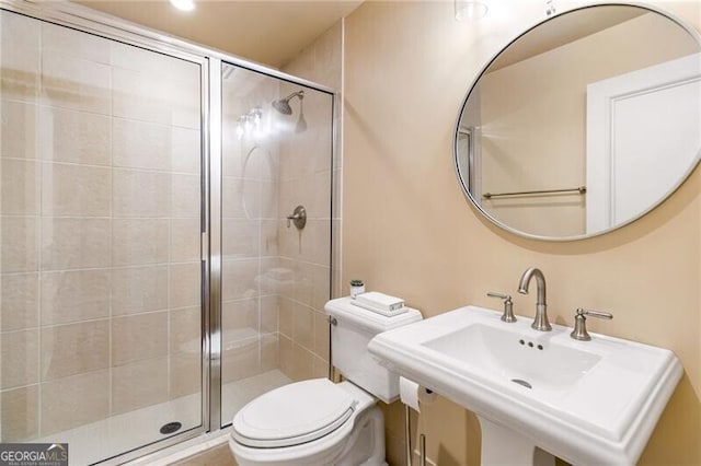 bathroom featuring toilet, sink, and a shower with door