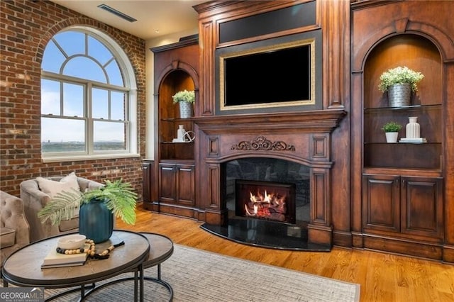 interior space featuring brick wall, light hardwood / wood-style floors, and a fireplace