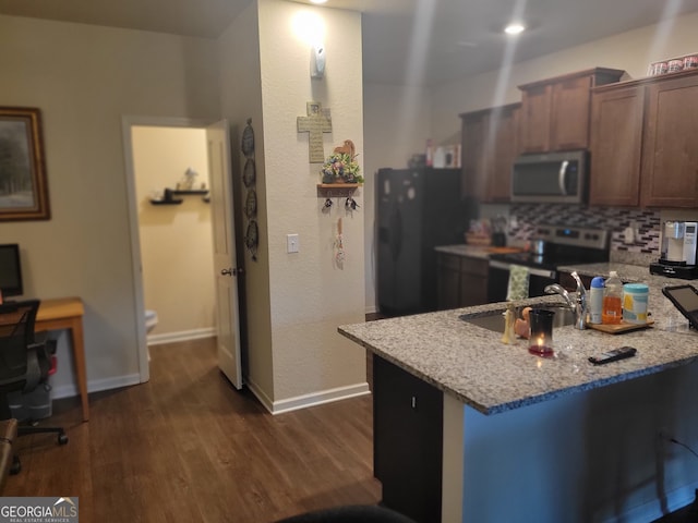 kitchen featuring backsplash, sink, dark hardwood / wood-style floors, light stone countertops, and appliances with stainless steel finishes