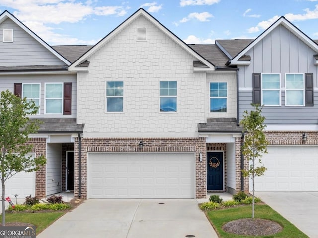 townhome / multi-family property with driveway, a garage, board and batten siding, and brick siding