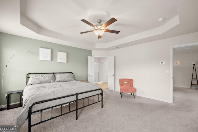 bedroom with light colored carpet, a tray ceiling, visible vents, and baseboards