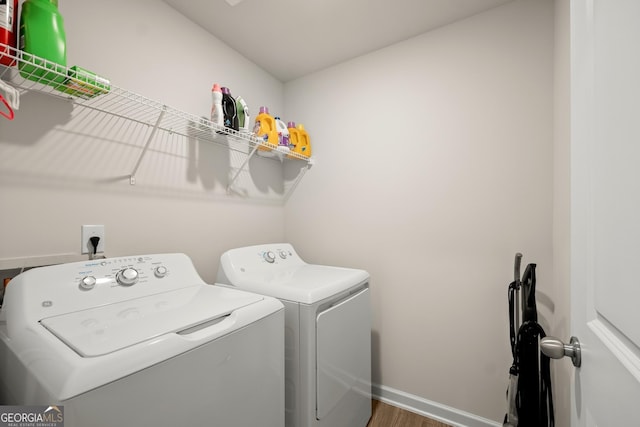 laundry area with laundry area, washing machine and dryer, baseboards, and wood finished floors