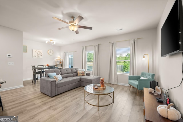 living room with visible vents, baseboards, ceiling fan, and light wood finished floors