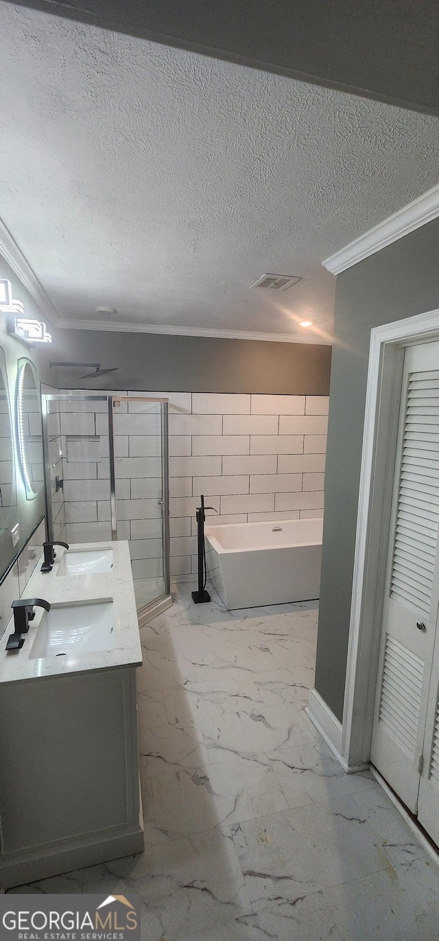 bathroom with a textured ceiling, vanity, crown molding, tile walls, and a tub