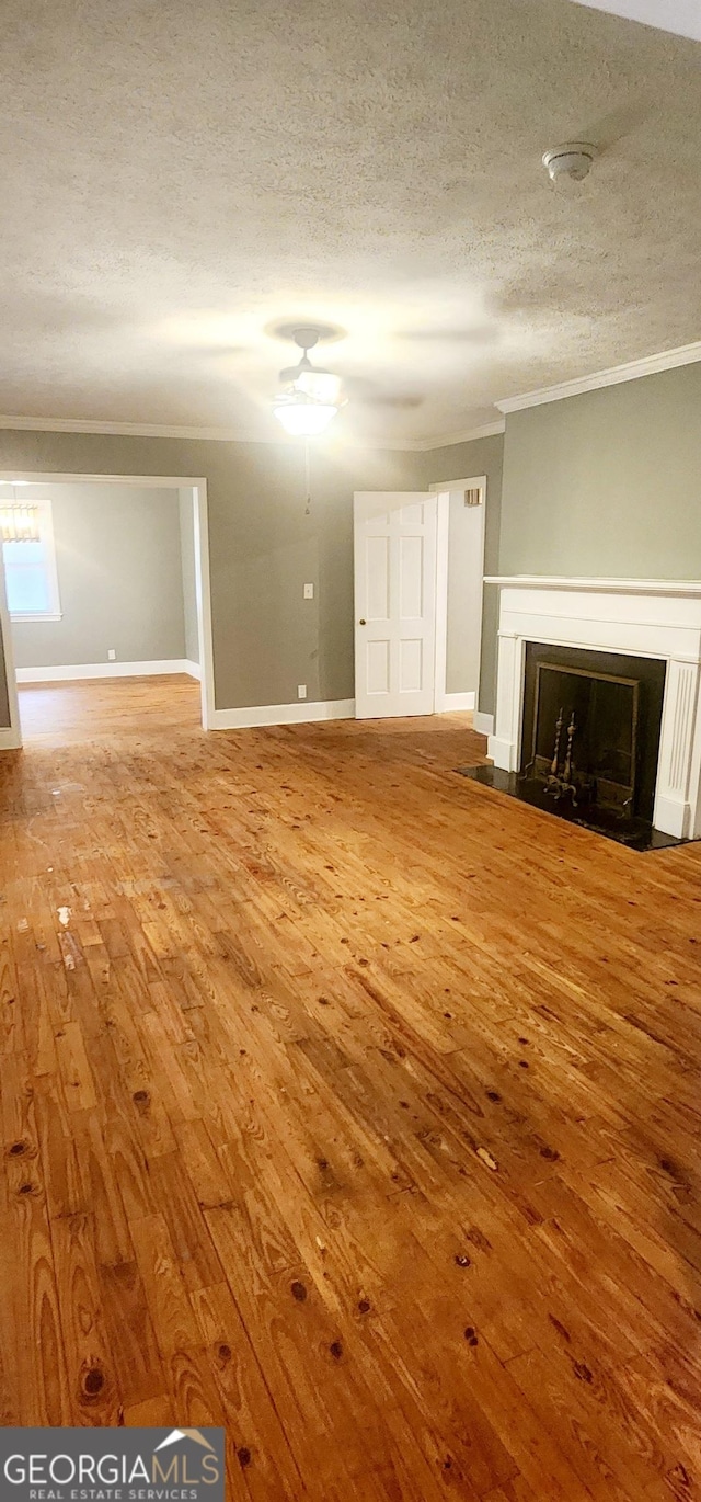 unfurnished living room with hardwood / wood-style floors, a textured ceiling, and ornamental molding