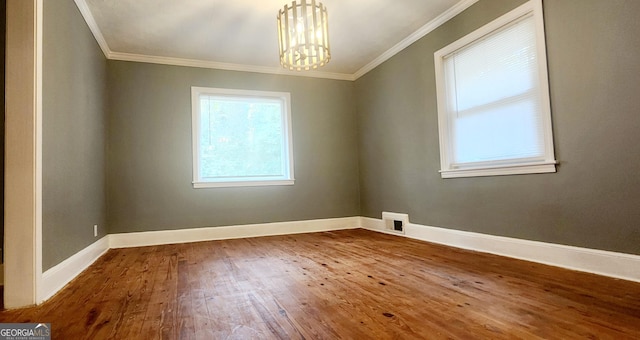 spare room featuring wood-type flooring, an inviting chandelier, and crown molding