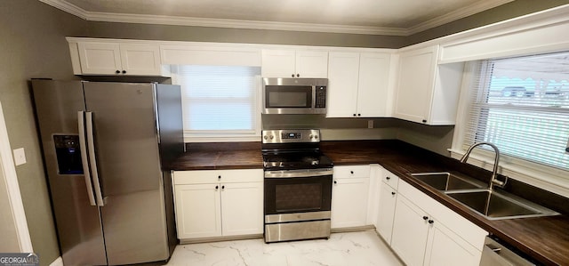 kitchen with white cabinetry, sink, ornamental molding, and appliances with stainless steel finishes