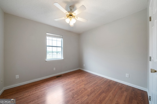 spare room featuring wood-type flooring, ceiling fan, and a textured ceiling