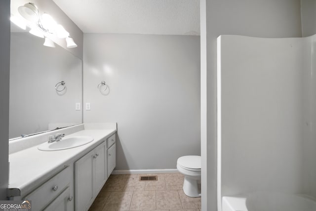 bathroom with toilet, vanity, a textured ceiling, and tile patterned flooring