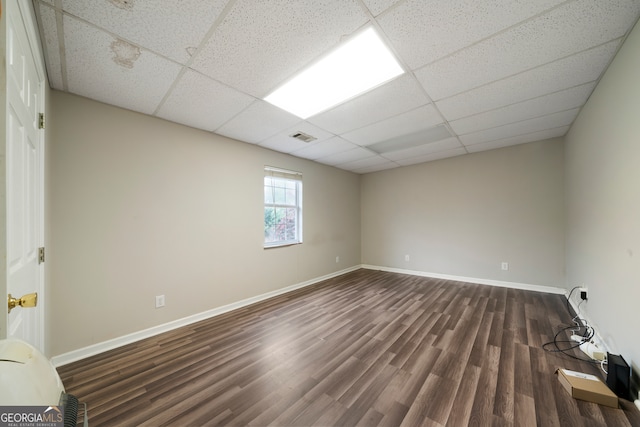 unfurnished room with a drop ceiling and dark hardwood / wood-style floors