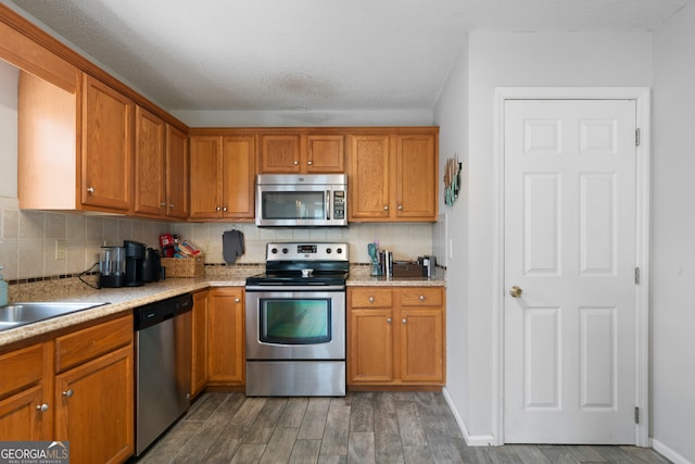 kitchen featuring stainless steel appliances, a textured ceiling, dark hardwood / wood-style flooring, sink, and decorative backsplash