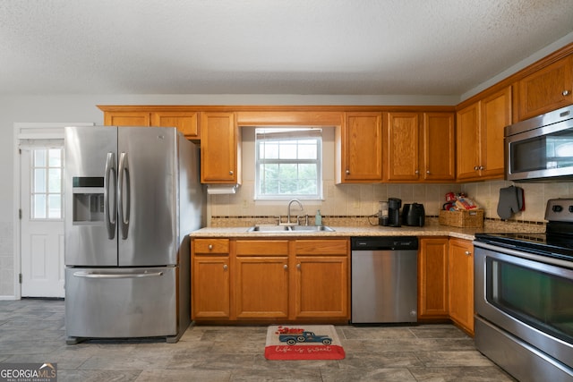 kitchen with stainless steel appliances, sink, tasteful backsplash, and light stone countertops