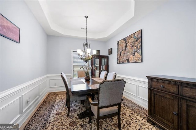 dining area featuring a notable chandelier and a raised ceiling