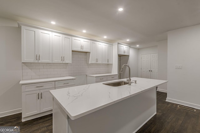 kitchen with dark hardwood / wood-style floors, white cabinetry, sink, and a kitchen island with sink