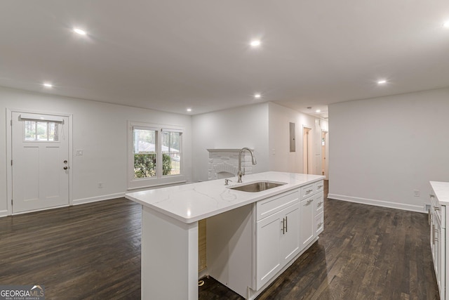 kitchen featuring light stone countertops, sink, dark wood-type flooring, a center island with sink, and white cabinets