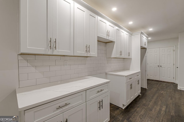 kitchen with backsplash, white cabinetry, dark wood-type flooring, and light stone counters