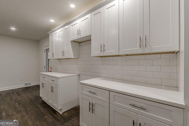 kitchen with white cabinets, light stone countertops, dark wood-type flooring, and tasteful backsplash