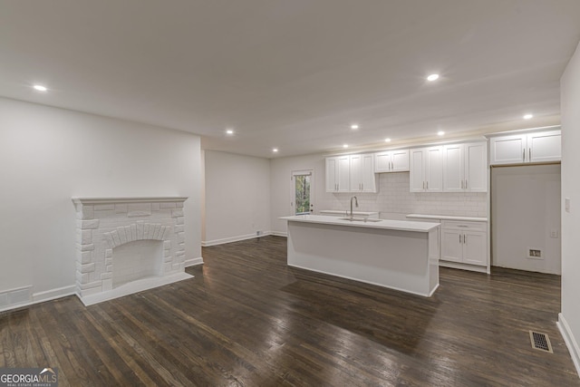 unfurnished living room featuring a brick fireplace, dark wood-type flooring, and sink