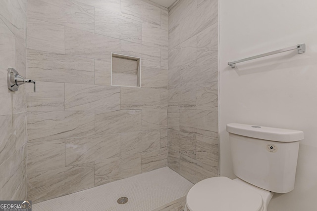 bathroom featuring a tile shower and toilet