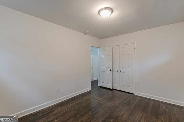 unfurnished bedroom featuring dark hardwood / wood-style flooring and a closet