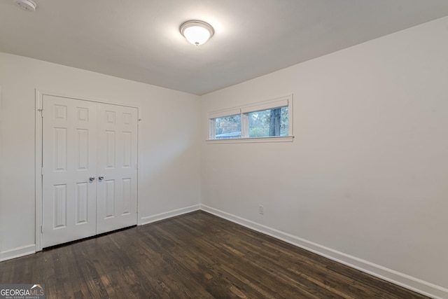 unfurnished bedroom with a closet and dark wood-type flooring