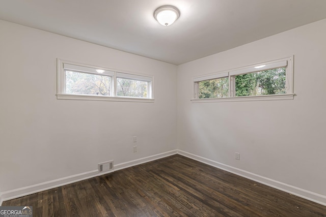 empty room featuring dark wood-type flooring and a healthy amount of sunlight